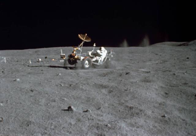 Astronaut in spacesuit driving lunar rover on lunar surface