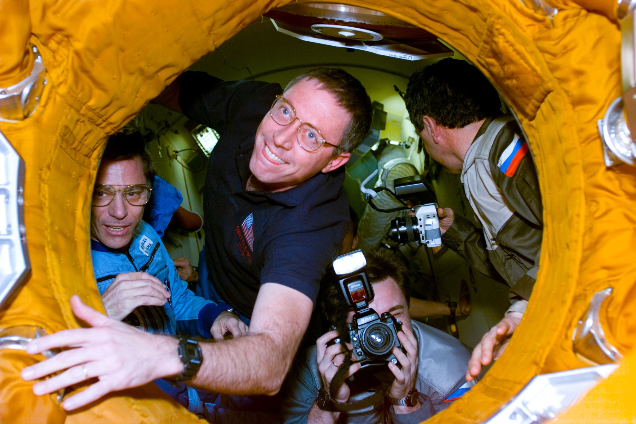 Astronauts in docking tunnel between Space Shuttle Atlantis and the Mir space station.