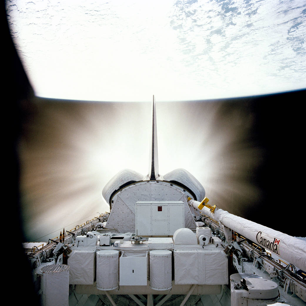 Shuttle Challenger in space with glowing engines visible and Earth in the background