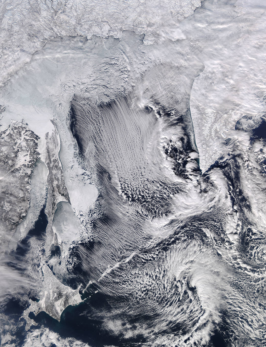 White parallel bands of clouds and snow covered sea ice imaged from satellite in orbit