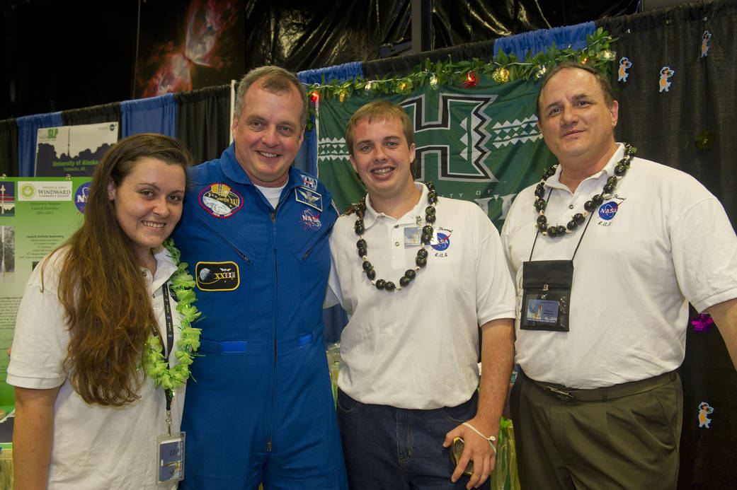 Students and team mentor standing with astronaut 
