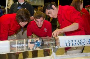Three students inspect rocket payload