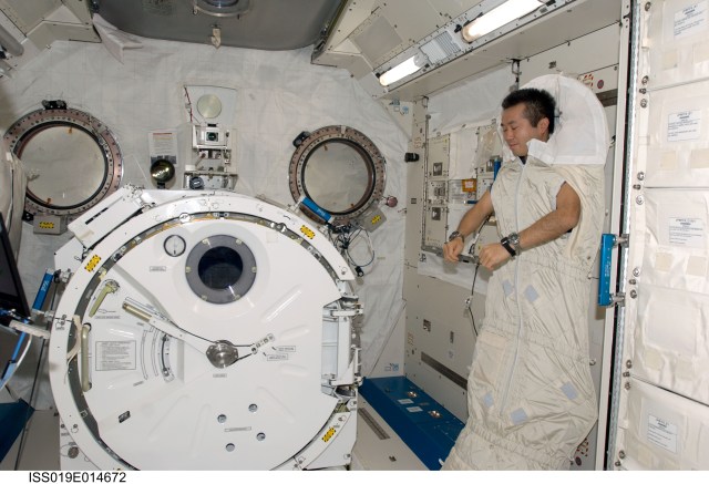 Japanese astronaut in a sleeping bag attached to the racks in the Kibo laboratory