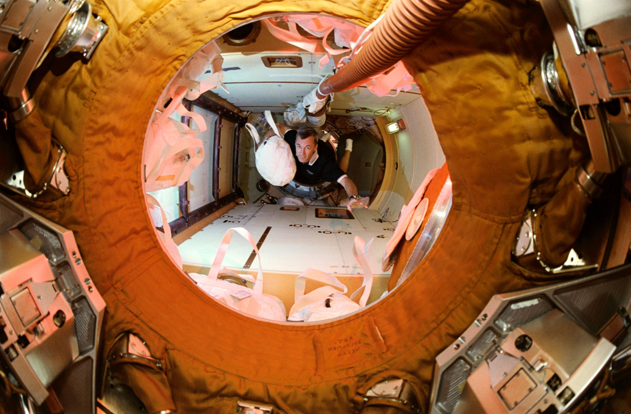 Astronaut Terrence W. Wilcutt traverses into Russia's Mir Space Station Kristall Module toting a water bag from the Space Shuttle Atlantis to be used on Mir