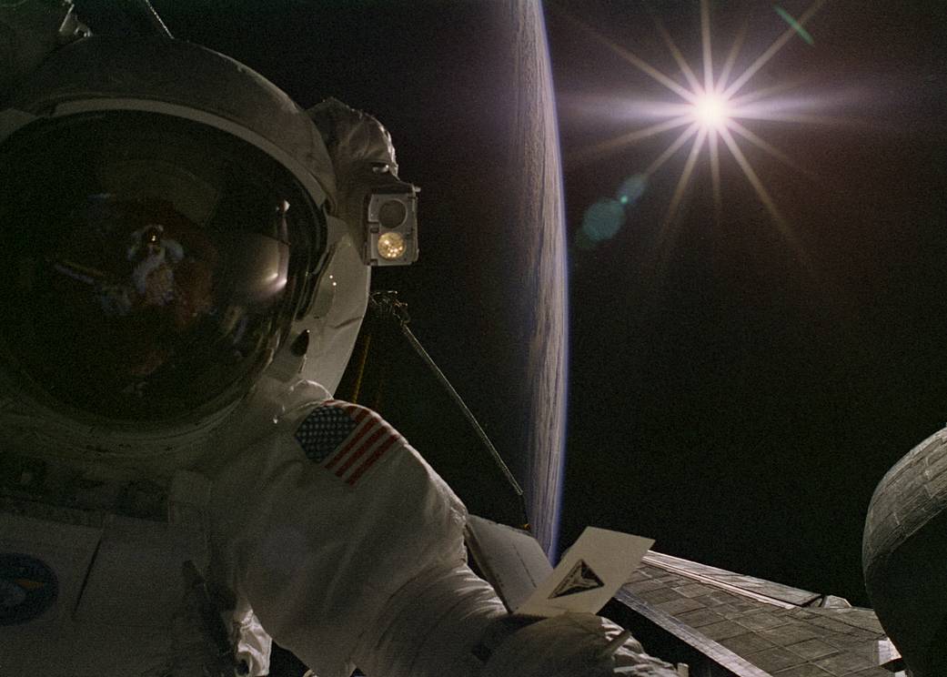 Astronaut on spacewalk with Earth and sun visible in background