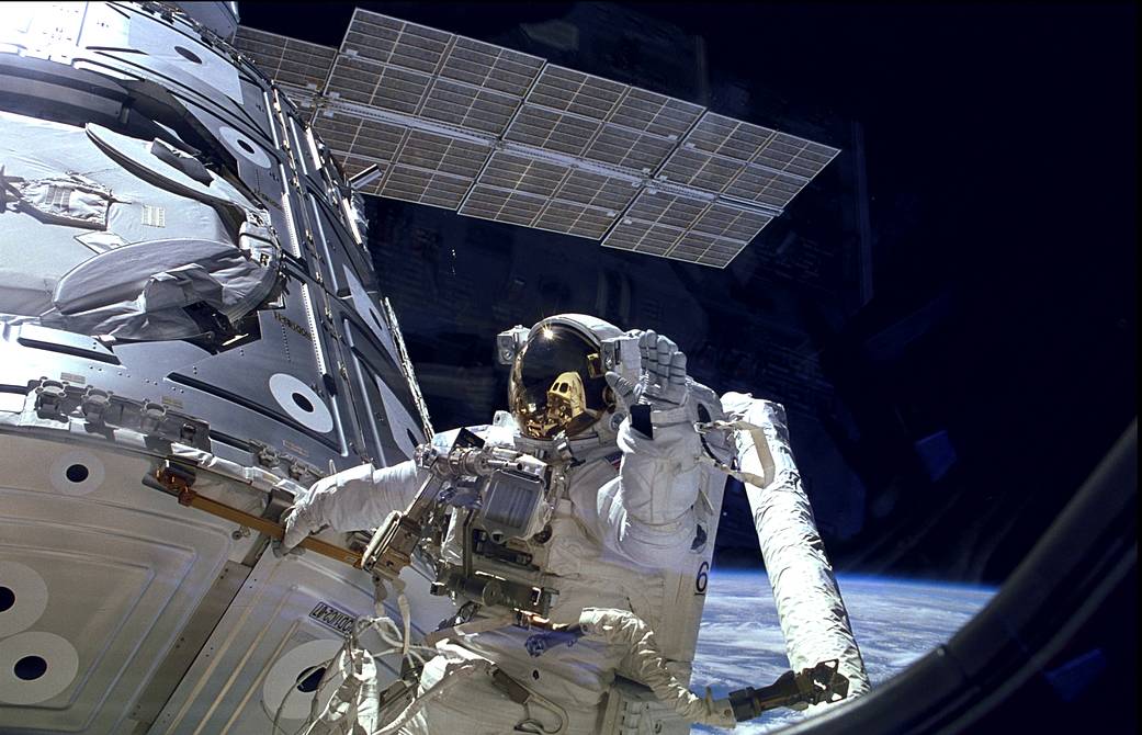 Astronaut James H. Newman waves during a spacewalk preparing for release of the first combined elements of the International Spa