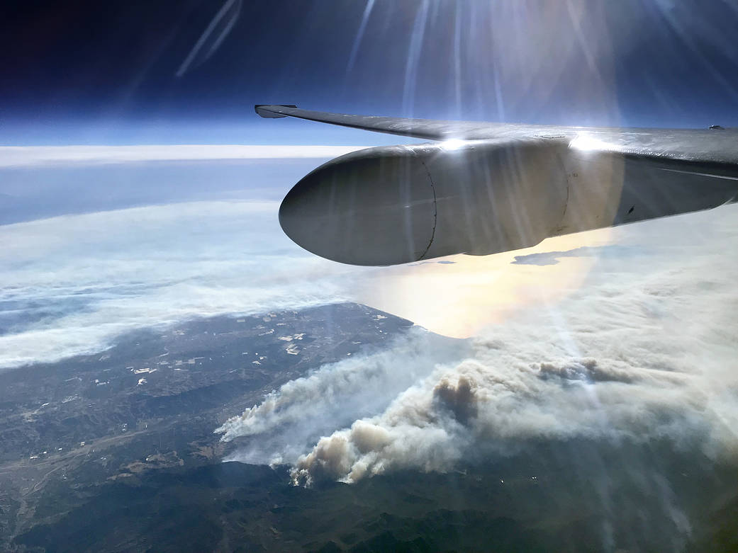 View from aircraft of smoke plume rising from land below