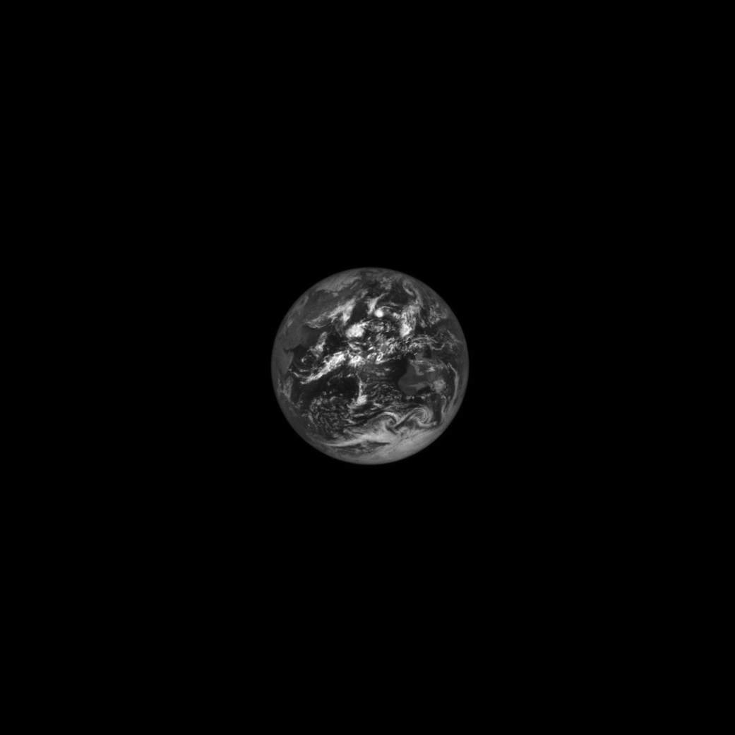 A grayscale image of Earth from space, like a gray marble with white swirls across its surface.