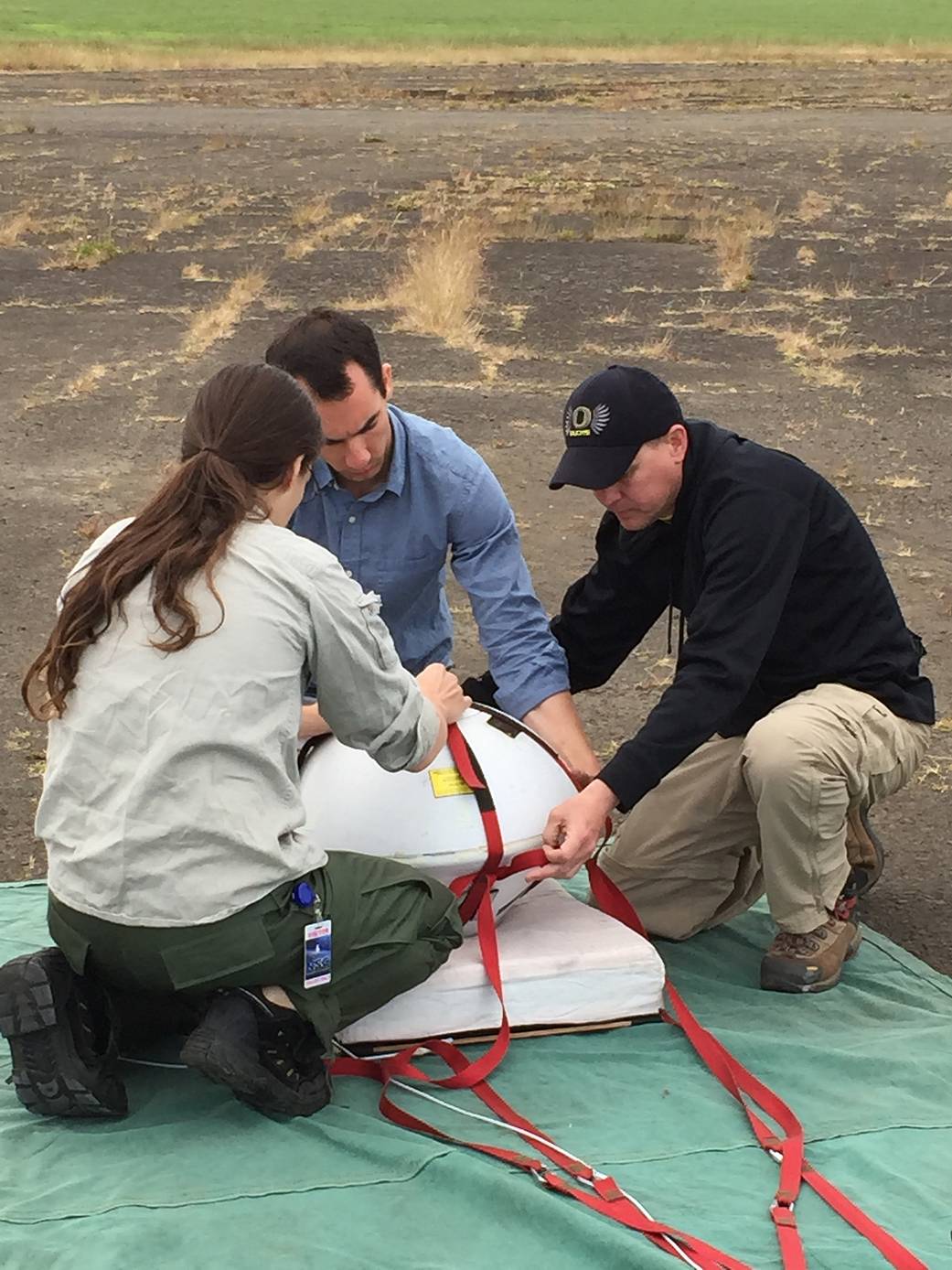 Technicians prepare an orbital entry return capsule for a test flight.