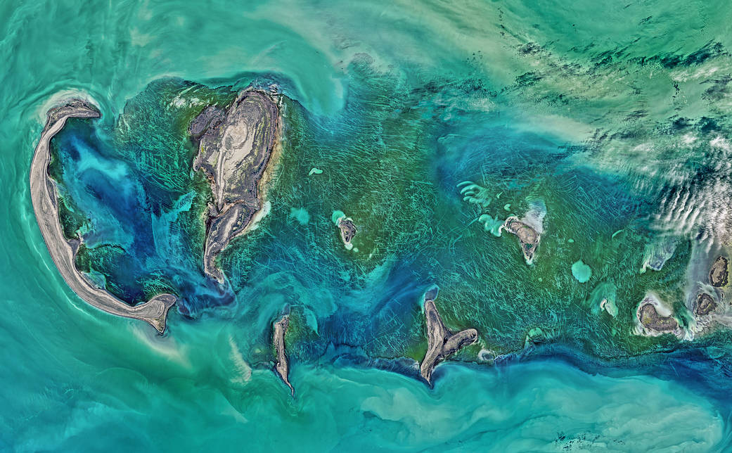 Satellite image of sea with islands and lines scoring along ice