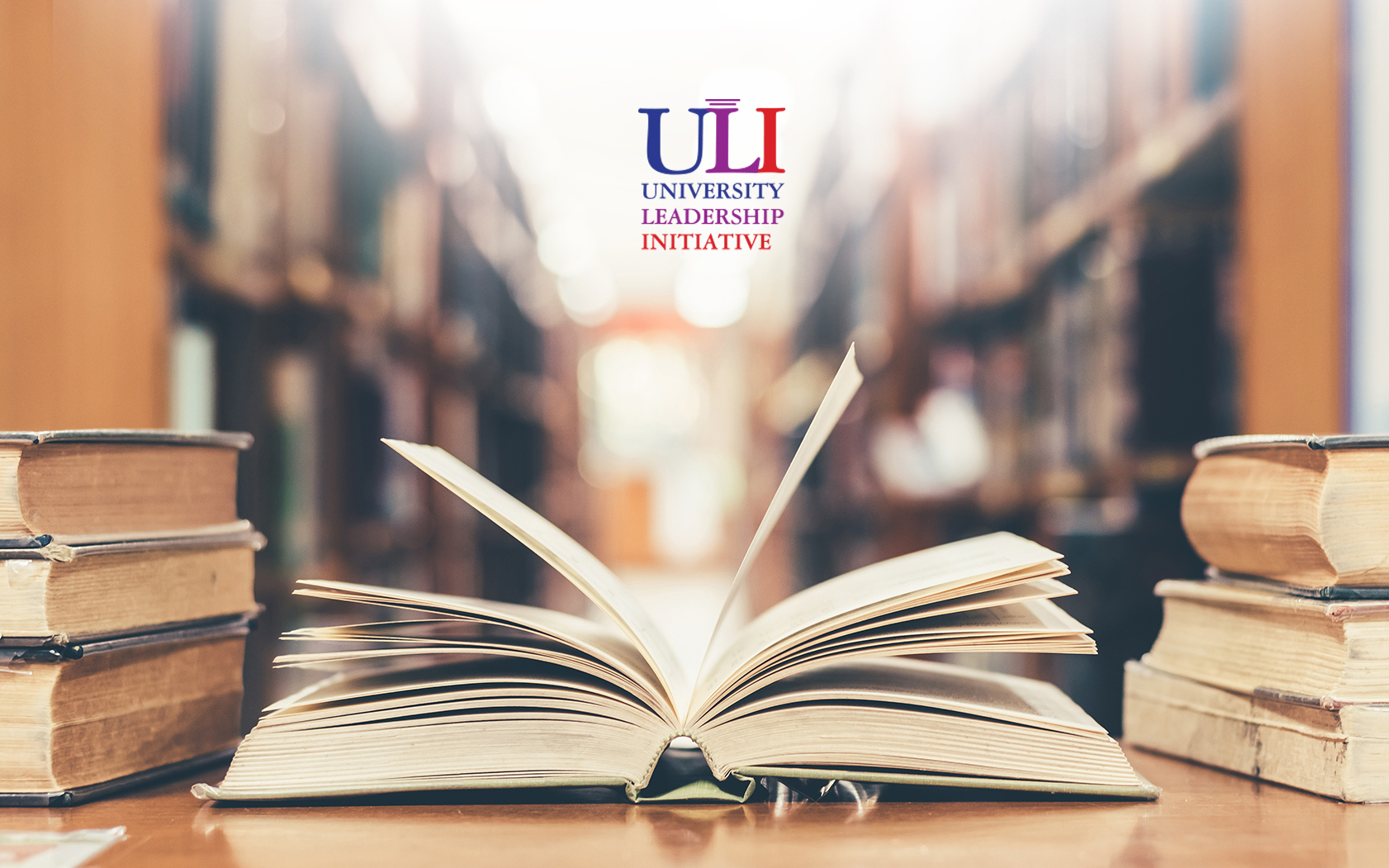 Books on a desk in a library with the text in the center that says ULI Univeristy Leadership Initiative.