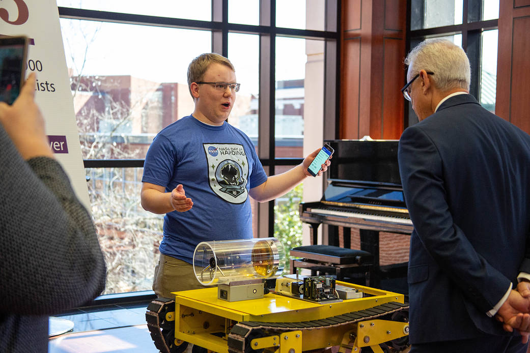 2 men talking with a robot between them