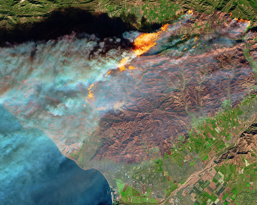 Satellite image of California coast showing smoke plumes and flames