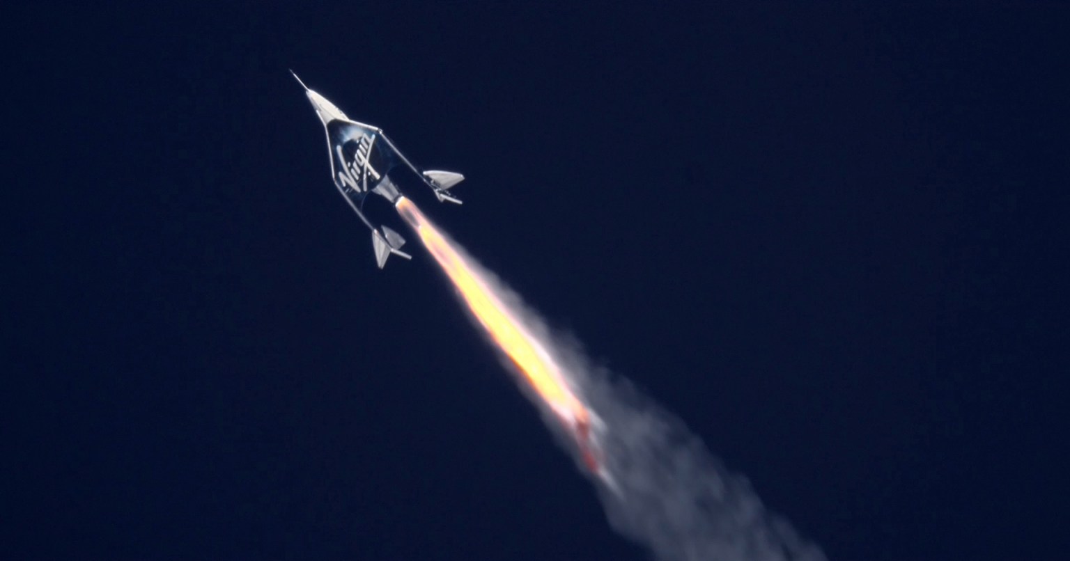 Spacecraft with "Virgin" written on the side rocketing through a deep blue sky