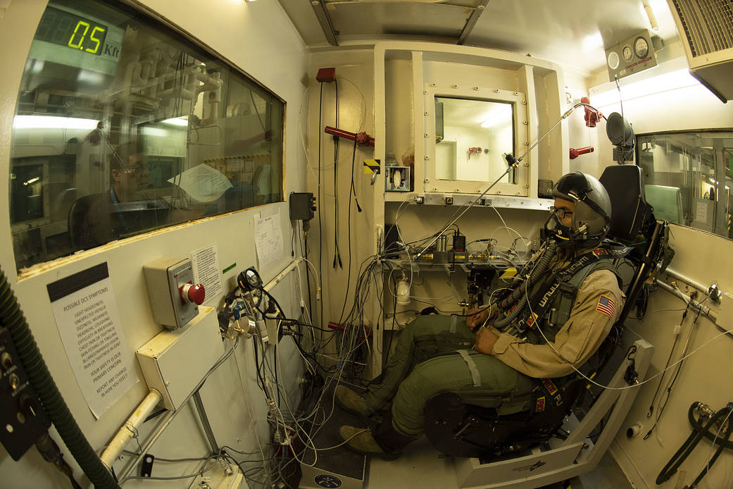 The test director runs through a check list as a military test volunteer prepares to undergo a rapid decompression test.
