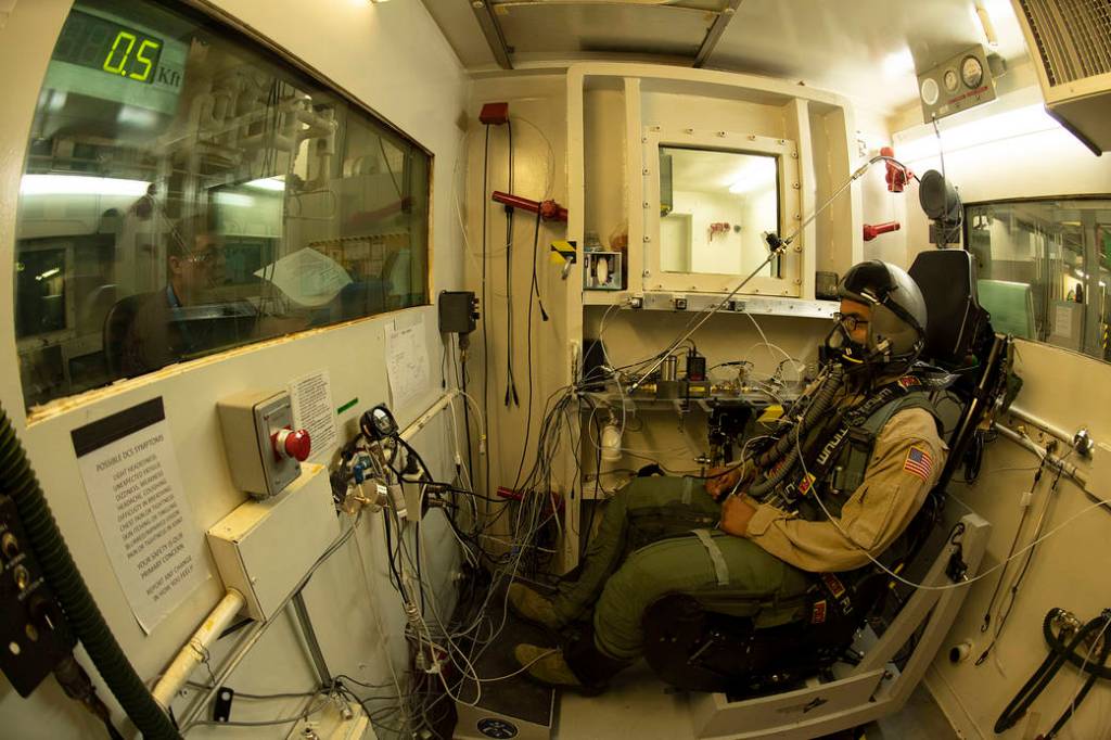 The test director runs through a check list as a military test volunteer prepares to undergo a rapid decompression test. 