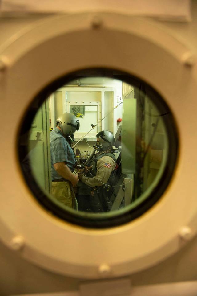 A KBR employee and a military test volunteer prepare for an altitude chamber flight that ensures the X-59 pilot’s safety at a variety of altitudes. 