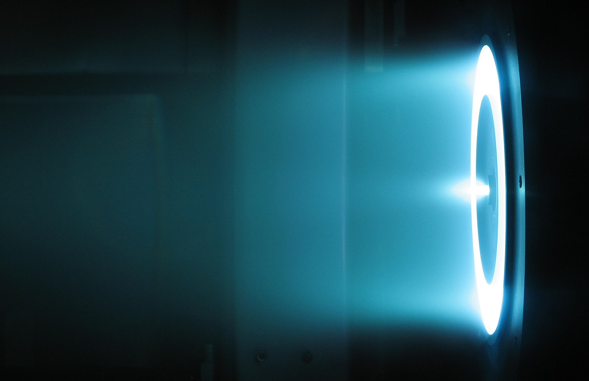 A solar electric propulsion Hall Effect thruster being tested under vacuum conditions at NASA.