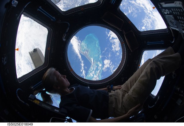 image of an astronaut enjoying the view of Earth below from the cupola inside the space station