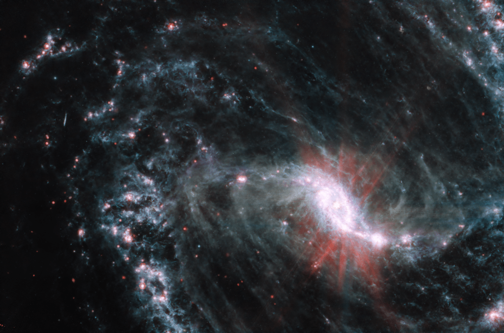 Scientists are getting their first look with NASA’s James Webb Space Telescope’s powerful resolution how the formation of young stars influences the evolution of nearby galaxies. NGC 1365, observed here by Webb’s Mid-Infrared Instrument (MIRI) is one of a total of 19 galaxies targeted for study by the Physics at High Angular resolution in Nearby Galaxies (PHANGS) collaboration. In the MIRI observations of NGC 1365, clumps of dust and gas in the interstellar medium has absorbed the light from forming stars and emitted it back out in the infrared, lighting up an intricate network of cavernous bubbles and filamentary shells influenced by young stars releasing energy into the galaxy’s spiral arms. The exquisite resolution from Webb also picks up several extremely bright star clusters not far from the core and newly observed recently formed clusters along the outer edges of the spiral arms. Additionally, the Webb images provide insights into how the orbits of stars and gas vary depending on where they form, and how this results in the population of older clusters outside the inner star-formation ring. NGC 1365 is a double barred spiral galaxy that lies about 56 million light years away from Earth. It’s one of the largest galaxies currently known to astronomers, spanning twice the length of the Milky Way across. MIRI was contributed by ESA and NASA, with the instrument designed and built by a consortium of nationally funded European Institutes (The MIRI European Consortium) and NASA’s Jet Propulsion Laboratory, in partnership with the University of Arizona.