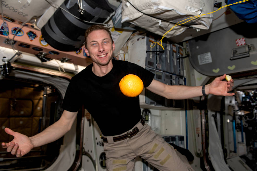 NASA astronaut and Expedition 68 Flight Engineer Woody Hoburg shows off a fresh orange, recently delivered aboard the SpaceX Dragon resupply ship, flying in microgravity aboard the International Space Station.