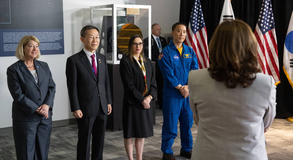 four people standing, with Vice President Harris' back to the camera; a golden mirror segment and US and ROK flags are in the background