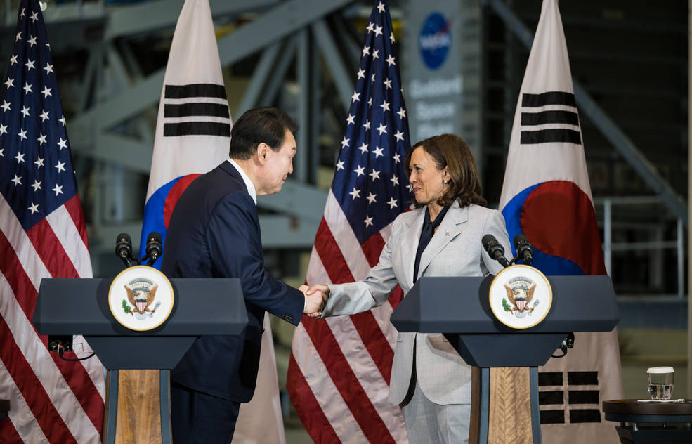 President Yoon and Vice President Harris shake hands at podiums, with American and Korean flags in the background