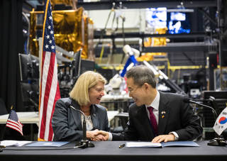 NASA Deputy Administrator Pam Melroy (left) and MSIT Minister Jong-ho Lee shake hands at a table with robotic equipment in the background