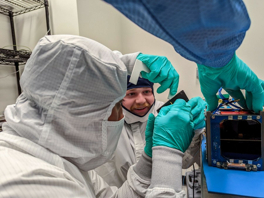 A pair of students install a solar array panel during the flight assembly of LightCube.