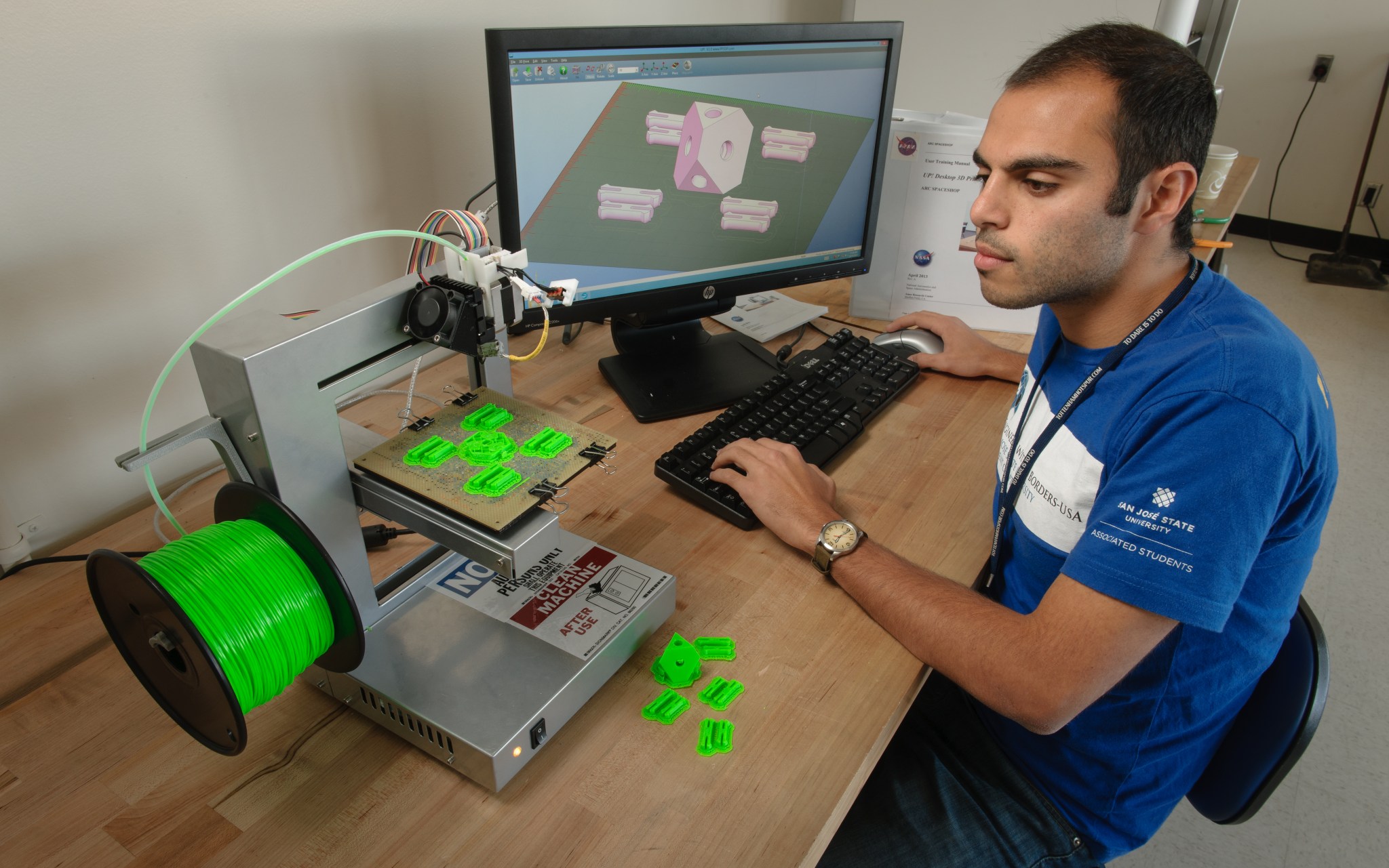 Arash Alex Mazhari, SpaceShop Student Intern, is using the 3D printer to print several plastic parts.