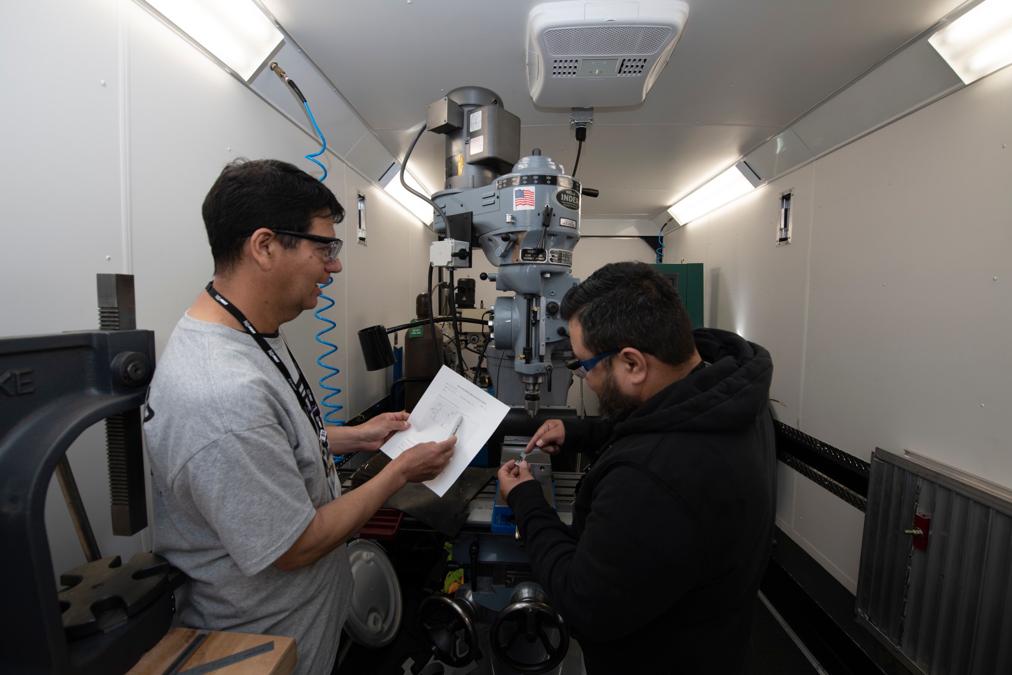 Two machinists work on a robotics part.