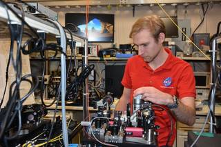 SCaN intern Christopher Nadeau adjusting equipment in the Quantum Metrology Lab at NASA’s Glenn Research Center.