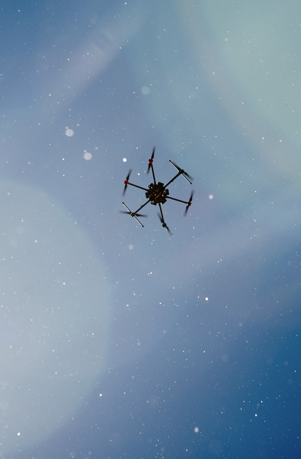 A drone in flight against blue skies.