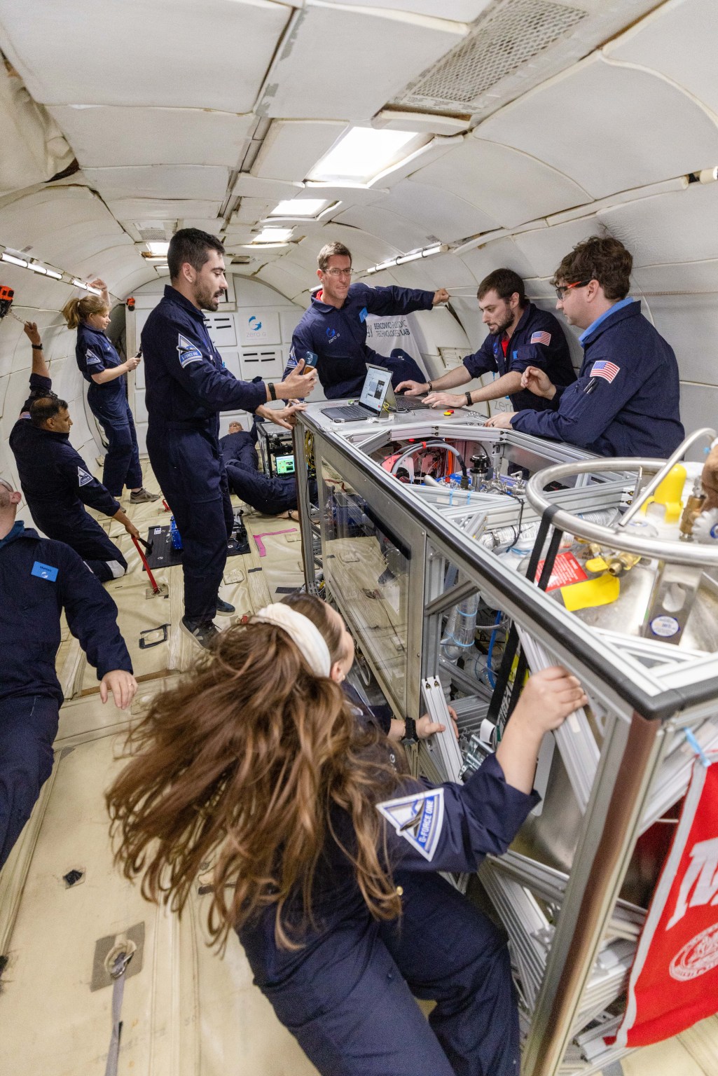 Five researchers run an experiment in microgravity, as indicated by one researcher's floating hair.