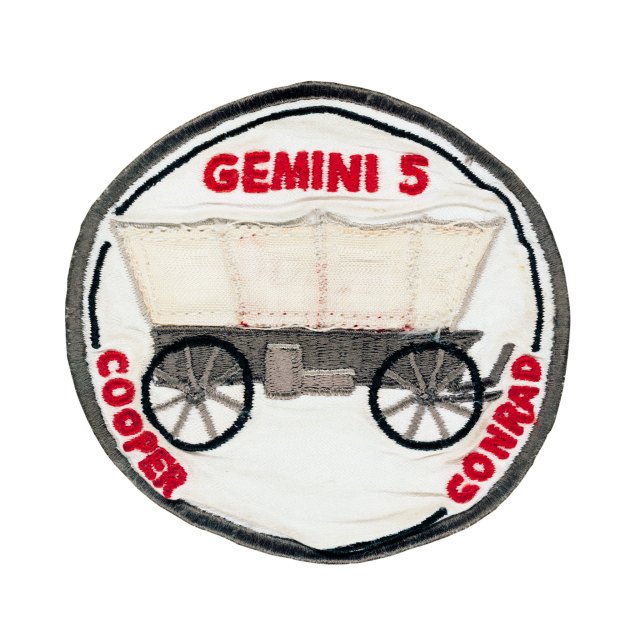 Mission patch for Gemini 5, with the names Cooper and Conrad along the edge, and a covered wagon shown in the center.