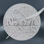 A close-up view of a 3D printed NASA logo is shown against a gray background.