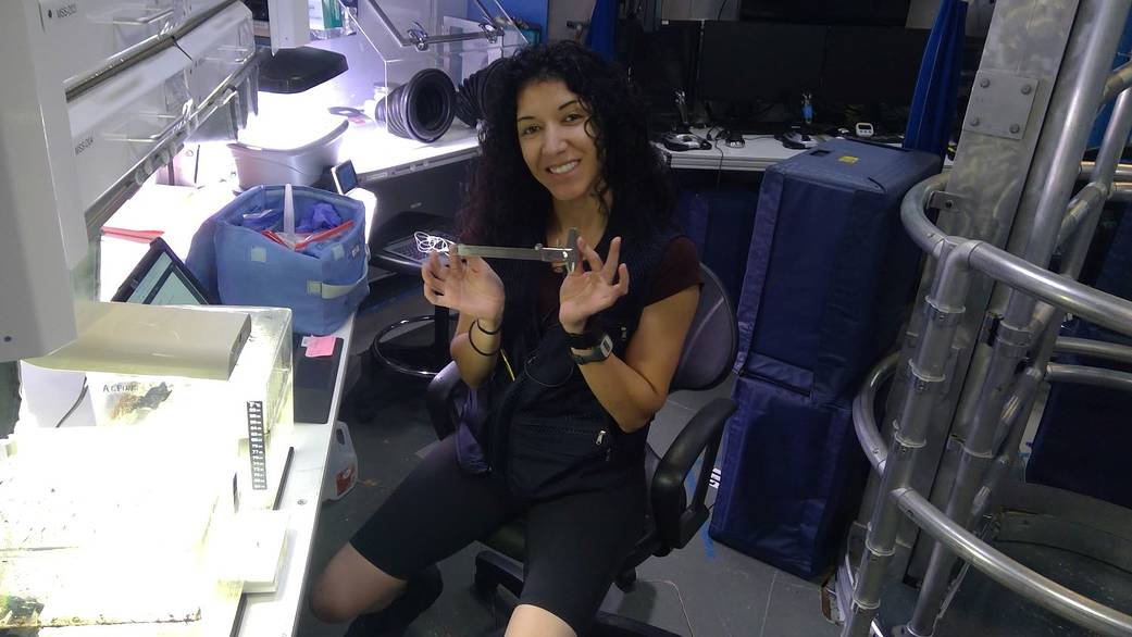 A HERA crew member Monique Garcia displays a device used to measure the size of tadpole shrimp raised in the habitat.