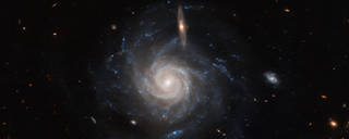 The barred spiral galaxy UGC 678 takes center stage in this image from the NASA/ESA Hubble Space Telescope. In the foreground, a smaller edge-on galaxy seems to bisect the upper portion.