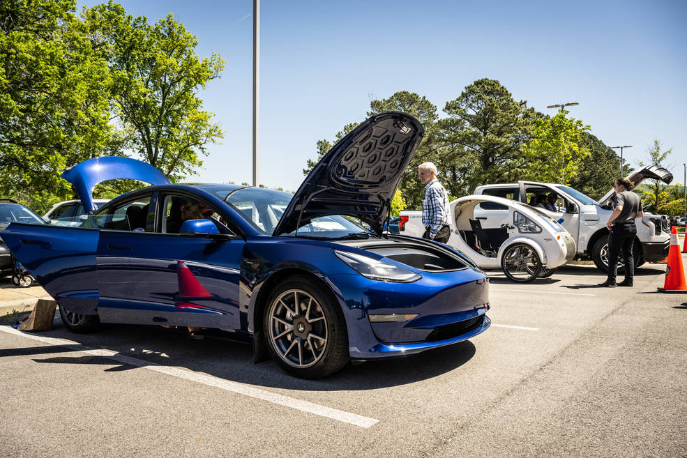 Attendees check out electric vehicles parked for display during a car show at Marshall’s Earth Day event.