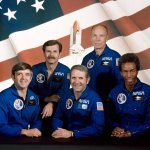 A picture of the STS-8 crew showing five astronauts in blue flight suits