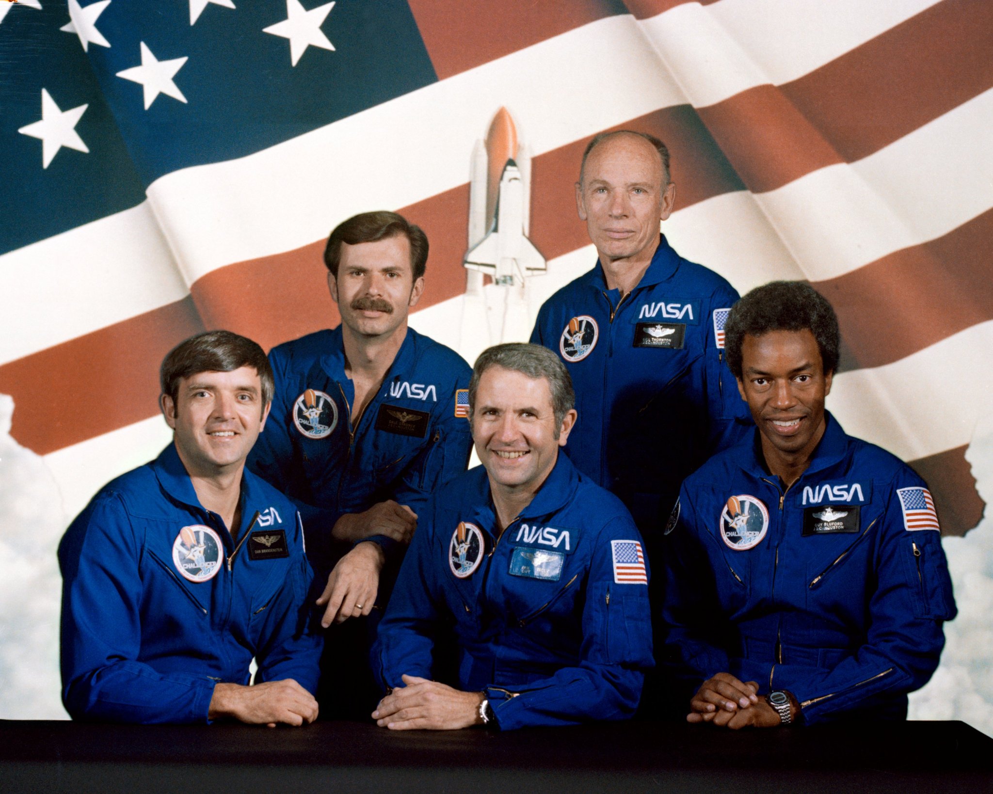A picture of the STS-8 crew showing five astronauts in blue flight suits