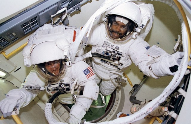 Two STS-63 astronauts in spacesuits preparing to exit the Shuttle airlock.