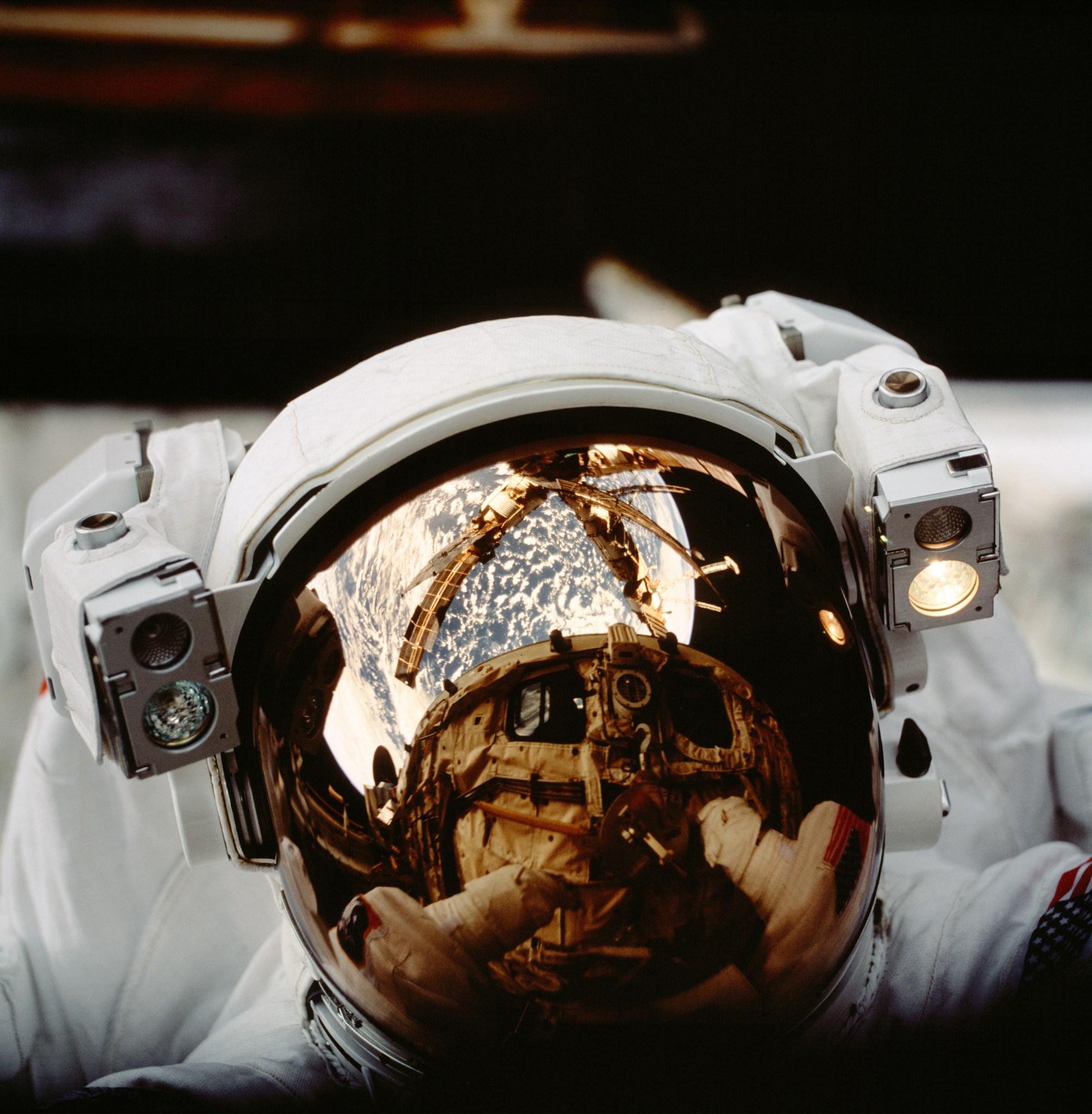 The helmet visor of astronaut Scott F. Parazynski reflects the space shuttle Atlantis’ cargo bay and Russia’s Mir Space Station as well as Earth’s horizon during an EVA.