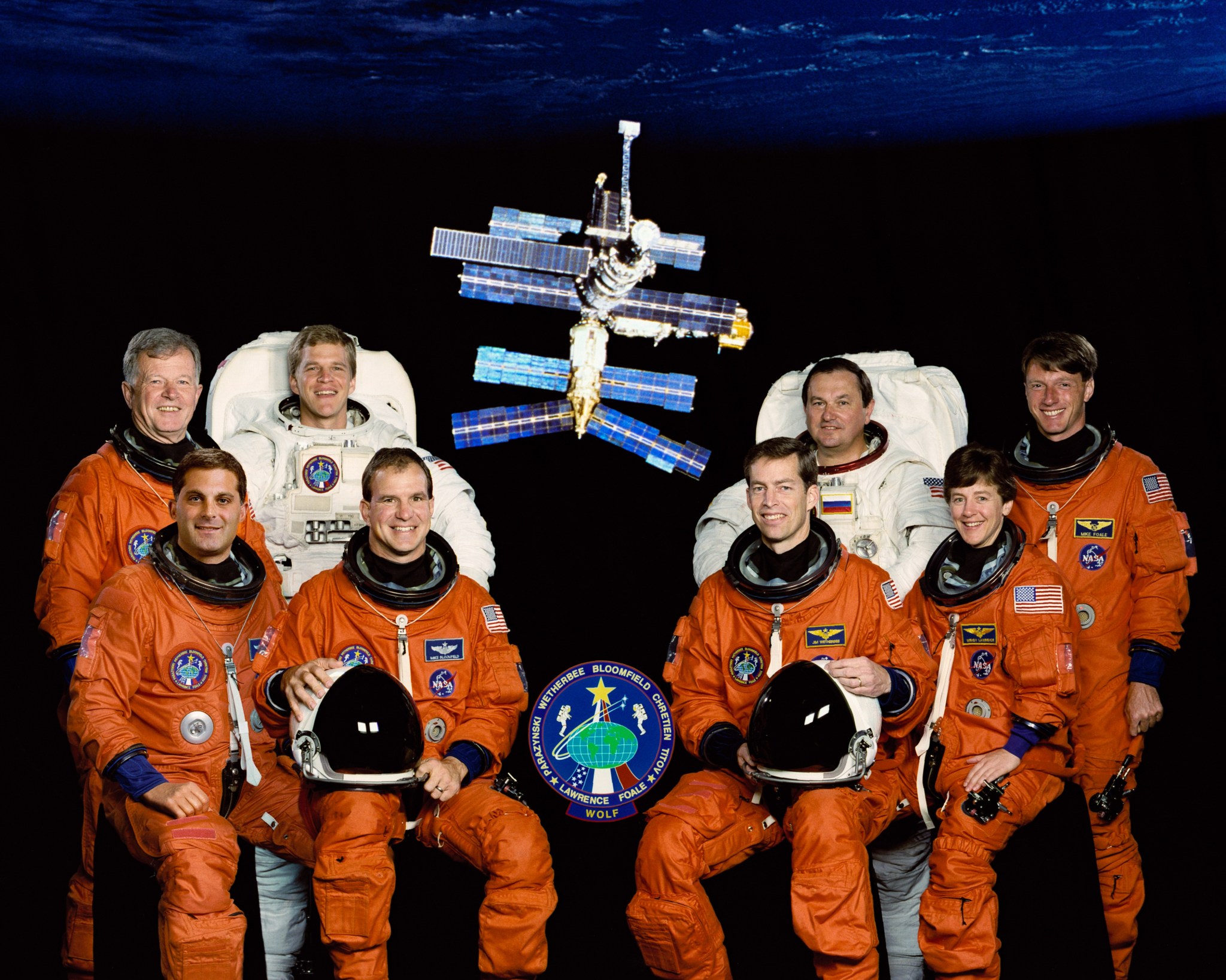 The official STS-86 crew portrait with a view of the Mir space station in the background.