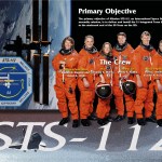 STS-112 crew poster with astronauts in orange flight suits, the mission patch, and the ISS with the primary objective