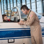 NASA Glenn Pilot smiles at young child and gives him a tour of plane inside the hangar.