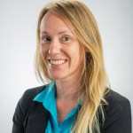 Portrait of Morgan Gilmour in a bright teal shirt and a black blazer over.