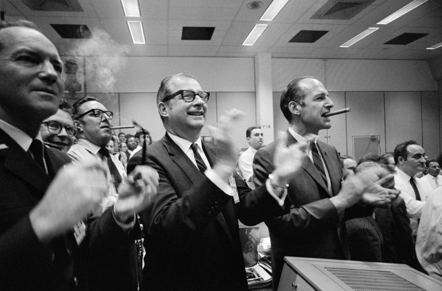 Men clap and smoke cigars in the control room after Apollo 13's safe landing