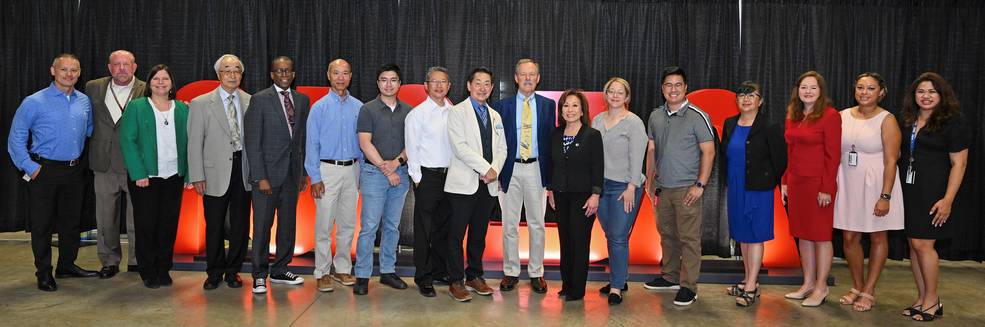 A group people stand in a line as they pose for a photo after an event at Marshall Space Flight Center.