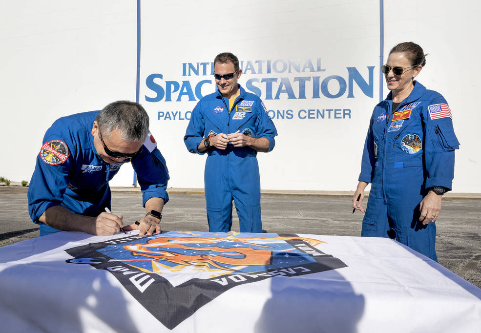 NASA’s SpaceX Crew-5 mission astronauts sign a flag emblazoned with their mission patch outside the Payload Operations Center for Marshall’s commercial crew support team members. 
